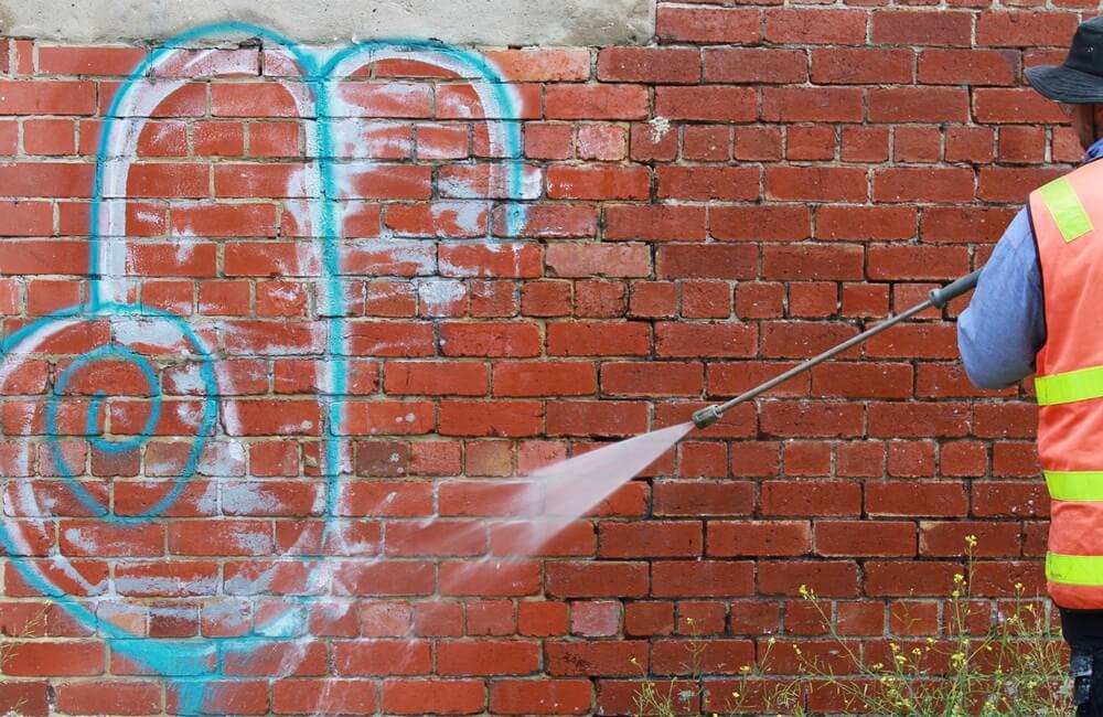 Removing graffiti from a brick wall in Bristol